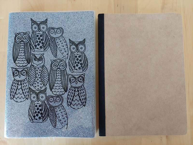 Photograph of a silver notebook cover with an owl design, alongside a plain Kraft notebook